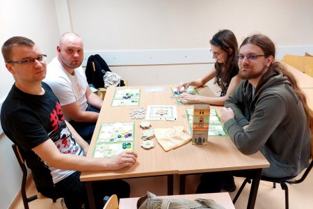 na zdjęciu osoby siedzące przy stolikach, grające w gry planszowe. Kliknij, aby powiększyć zdjęcie.